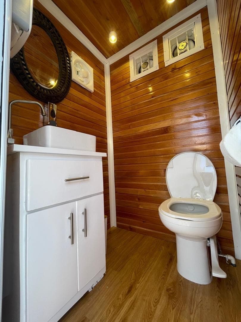 Finished trailer interior — timber cladding, round mirror and vanity basin